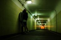 Man in Black Jacket and Black Shorts Walking on Hallway