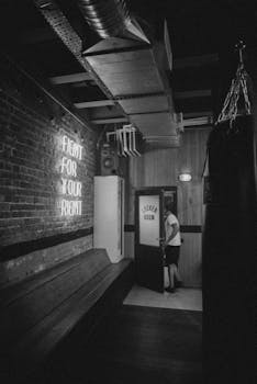 一张单色图像中，一个人走进了带有霓虹灯的健身房更衣室