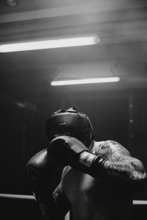Free Intense black and white shot of a tattooed boxer training indoors in a gym. Stock Photo