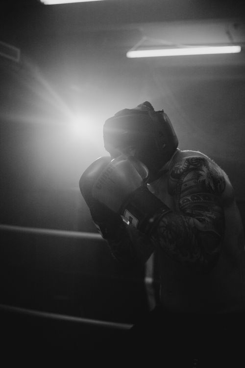 Free A boxer trains in a dimly lit gym, captured in black and white with strong contrasts. Stock Photo