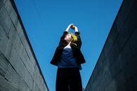 在城市的地下通道里，一位黄发女子举起双臂摆着姿势，天空蔚蓝
