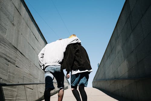 Man in White Shirt and Black Jacket Walking on Street