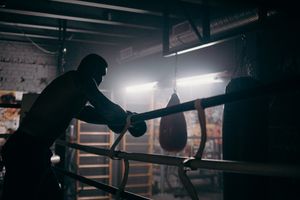 Fighter on the ropes in a dim gym — photo by cottonbro studio on Pexels