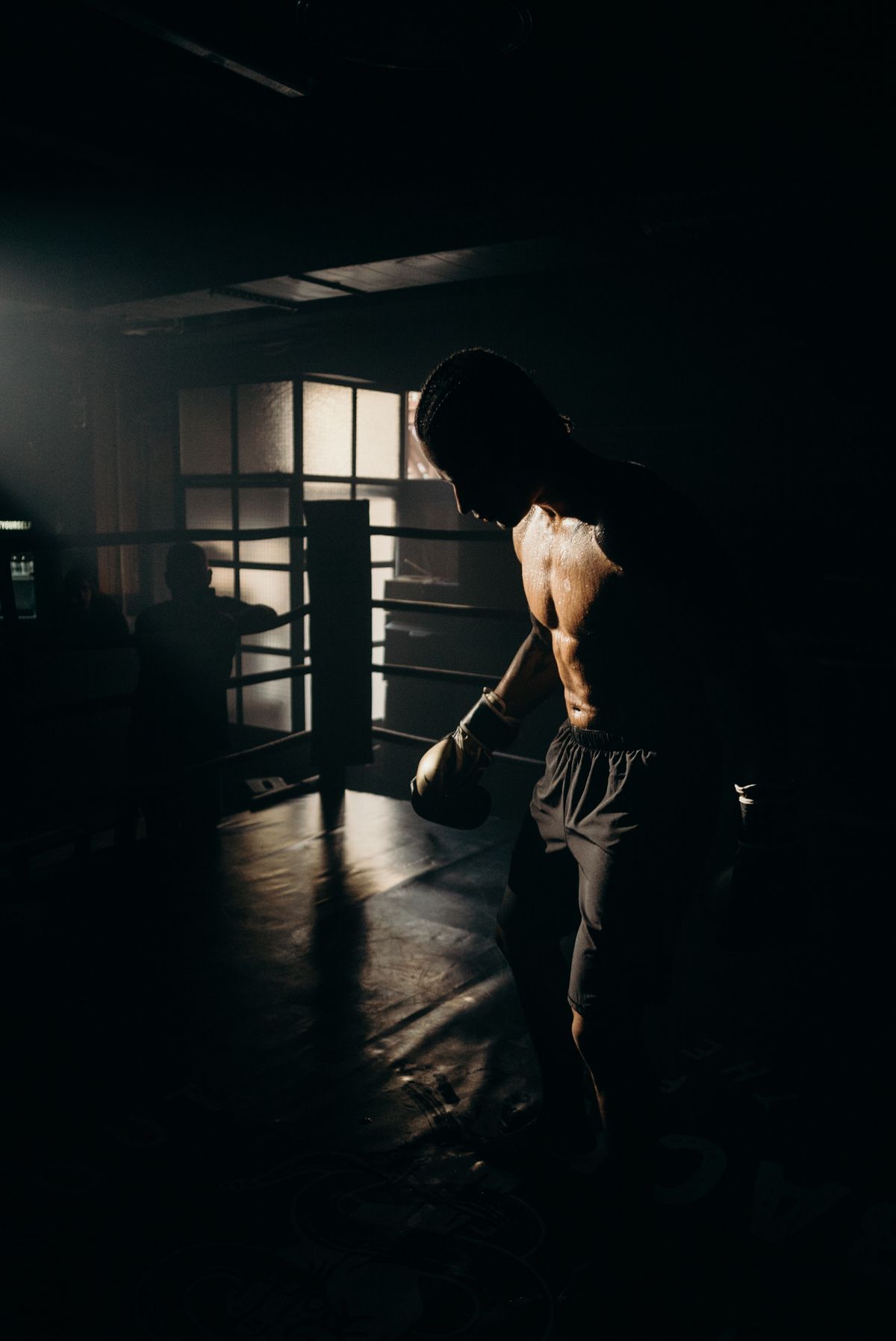 Boxer silhouette backlit in a dark gym