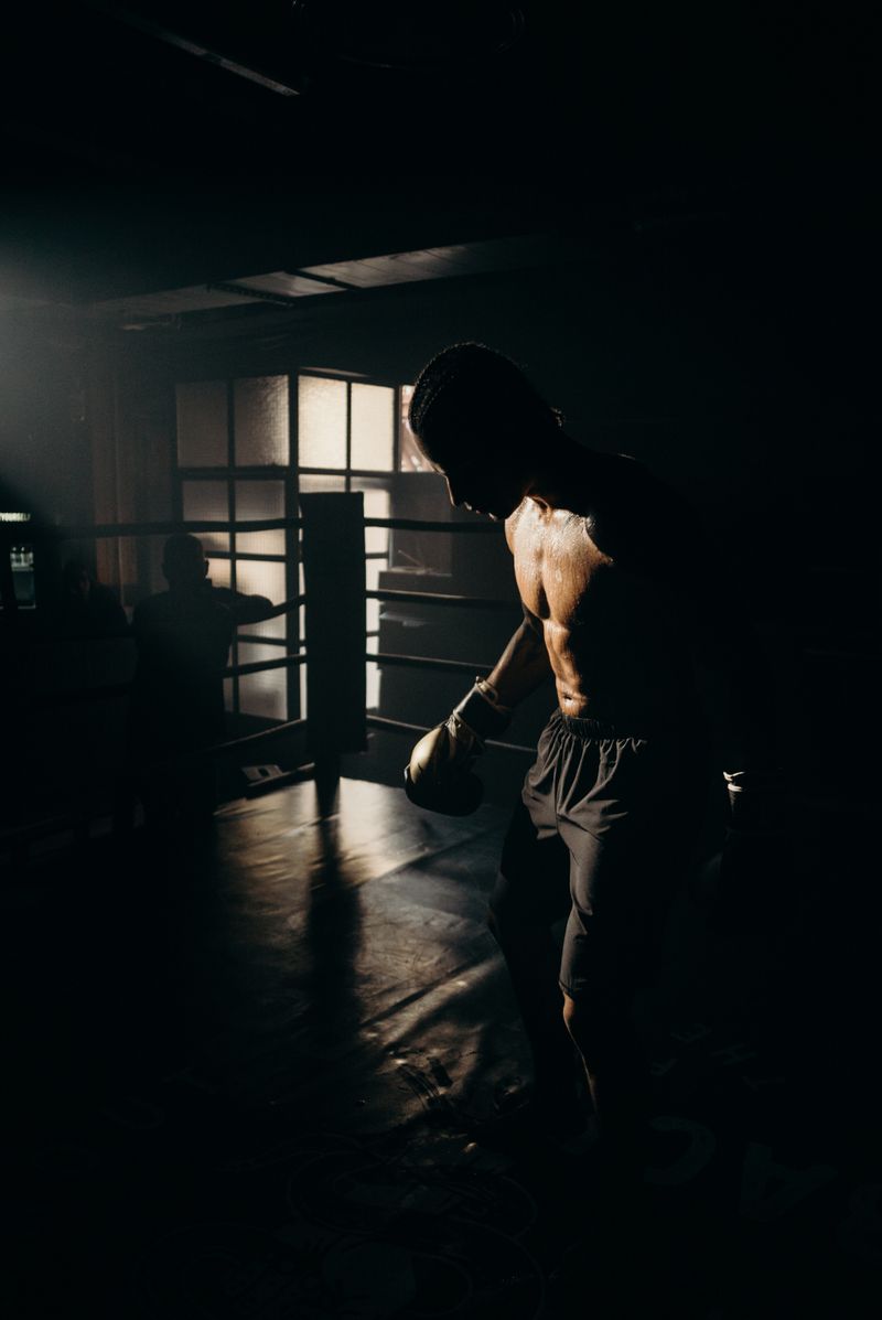 Silhouetted boxer training under dramatic lighting — photo by cottonbro studio on Pexels