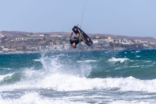 Free A thrill-seeking kiteboarder performs a high-flying trick above Maspalomas beach waves. Stock Photo