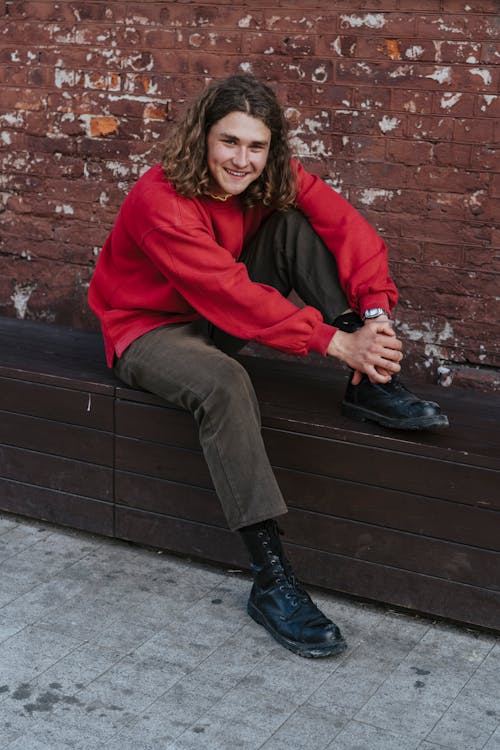 Man in Red Sweater Sitting on Brown Bench