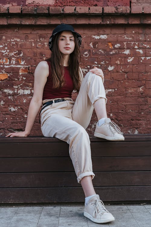 A Girl Wearing a Bucket Hat Sitting on a Wooden Seat