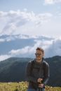 一名戴着墨镜的男子在多云的天空下微笑着徒步登山