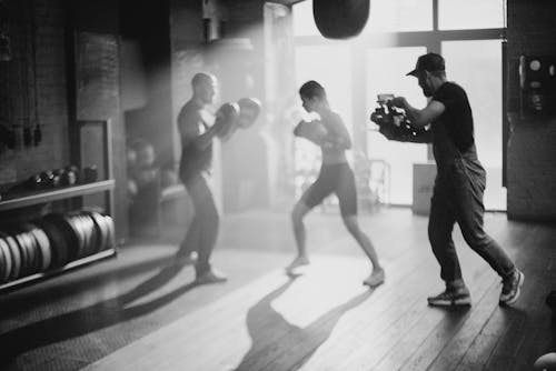 Grayscale Photo of 2 Men and Woman Doing Exercise