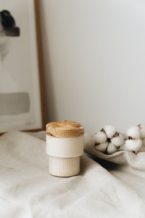 Free A stylish dalgona coffee cup placed next to cotton flowers on a fabric surface. Stock Photo