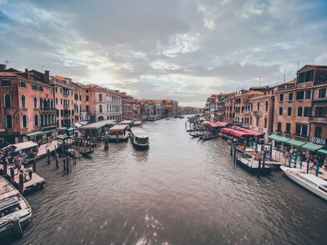 From above of beautiful view of grand canal with vessels floating between old buildings of coastal city against cloudy sky