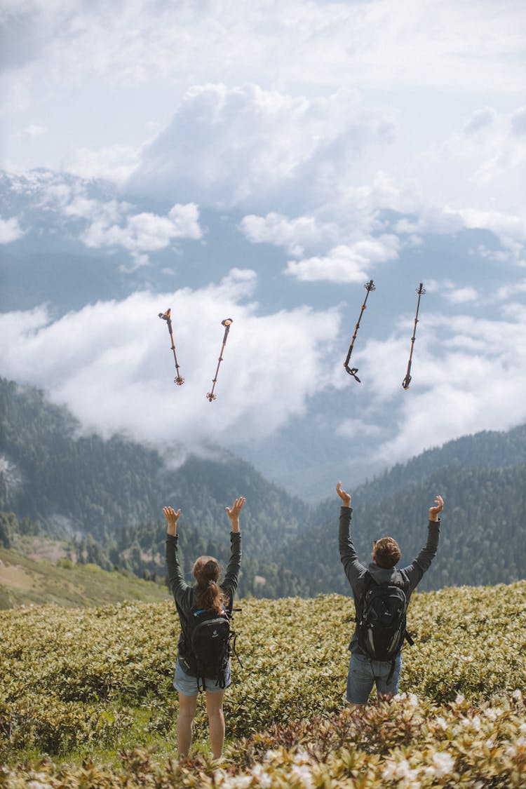 A Couple Throwing Their Trekking Poles In The Air