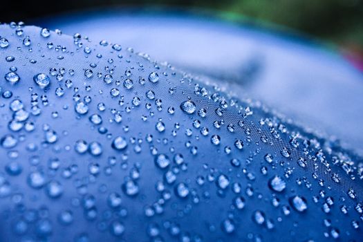 Close-up macro shot of water droplets on a smooth blue surface, emphasizing texture and clarity.