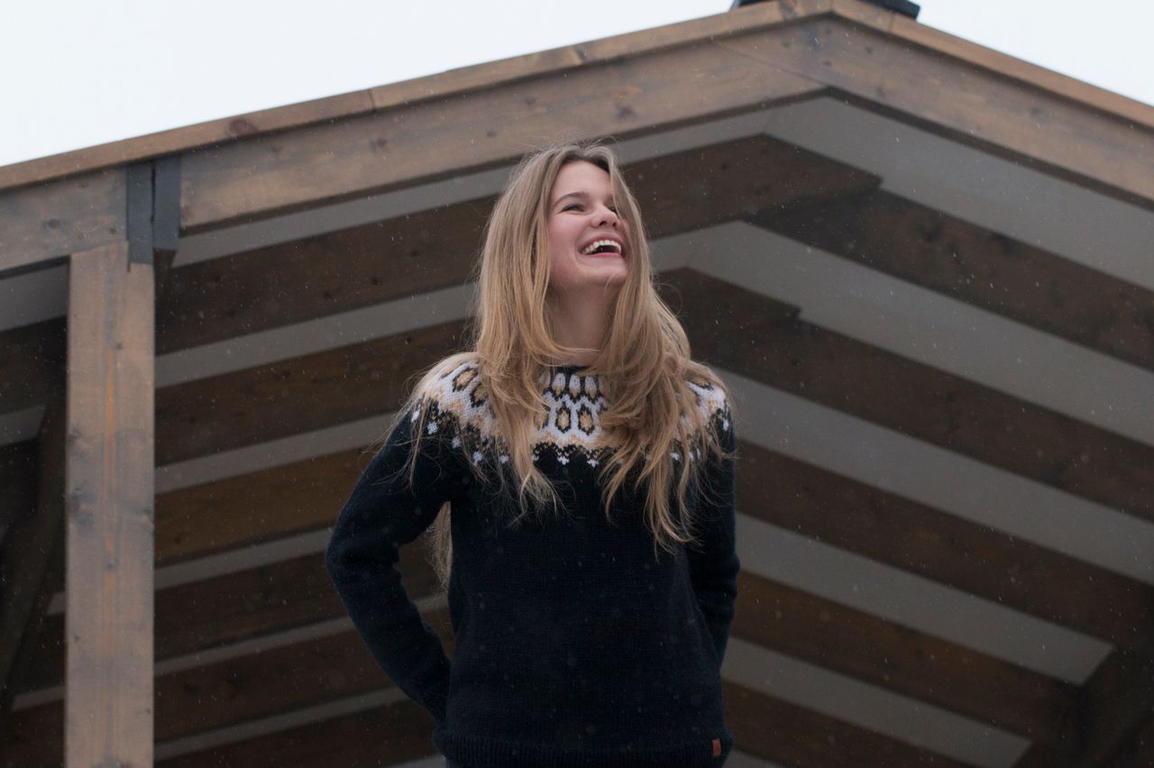 Smiling woman in a Nordic-pattern knit sweater outdoors