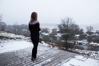 Woman Standing on Snowy Rooftop Overlooking River
