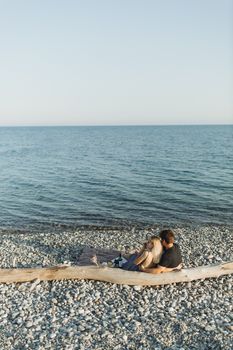 日落时分，情侣们在海边的鹅卵石滩上享受浪漫时刻