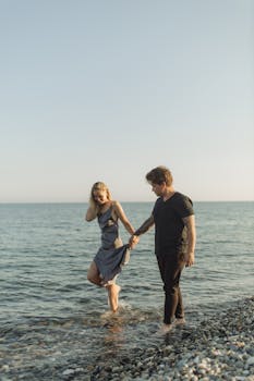 日落时分，一对夫妇在鹅卵石海滩上漫步，十分浪漫