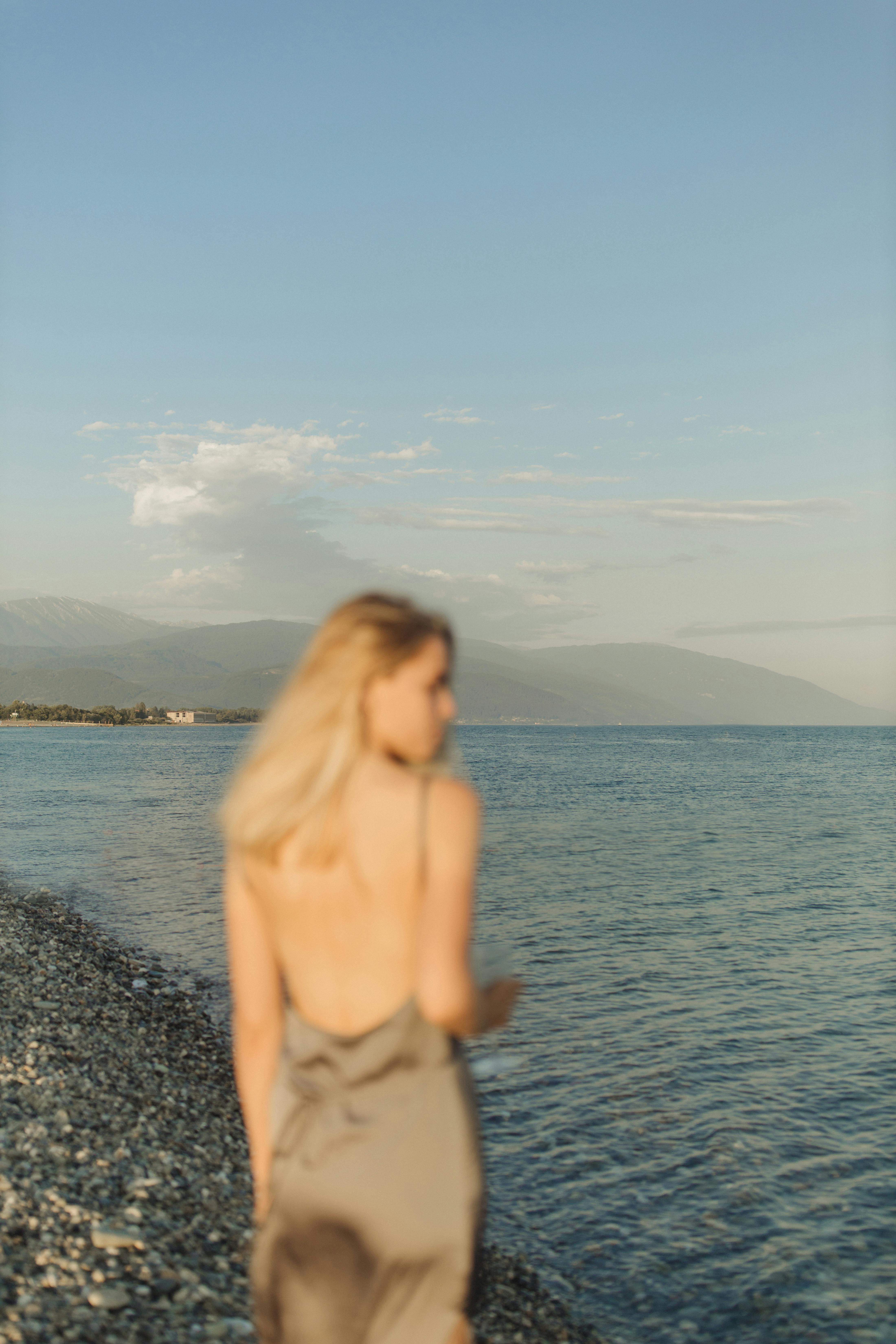 topless woman standing on rocky shore