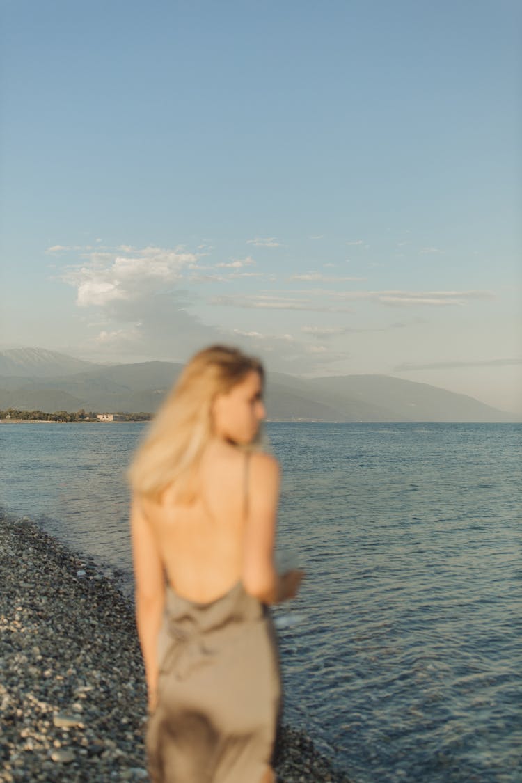 Topless Woman Standing On Rocky Shore