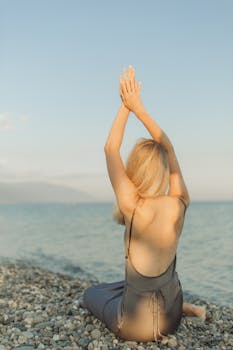Woman practicing yoga alone on a secluded beach during sunset, enjoying a peaceful and reflective moment by the sea.