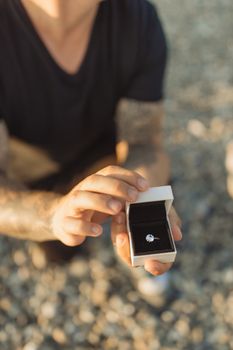 一名男子在海滩上赠送订婚戒指，营造出浪漫的求婚氛围