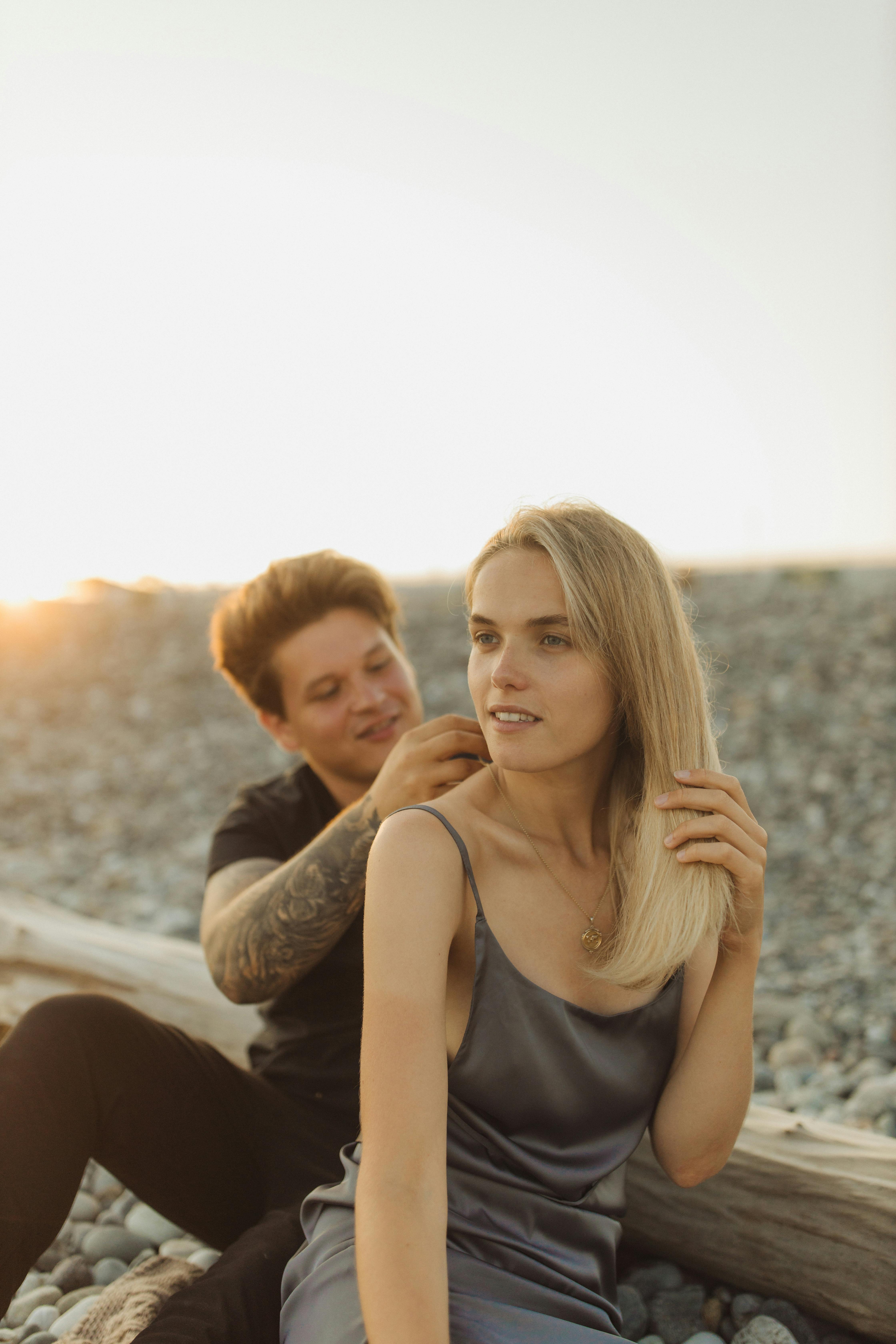 A loving couple enjoying a romantic moment on a pebble beach during sunset.