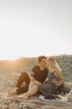 日落时分，一对夫妇在岩石海滩上享受浪漫野餐，营造出温柔时刻