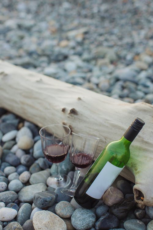 Wine Bottle Beside Wine Glass on Brown Wooden Table