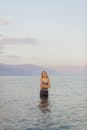 日落时分，一名女子平静地站在海里，周围是宁静的自然和柔和的色彩