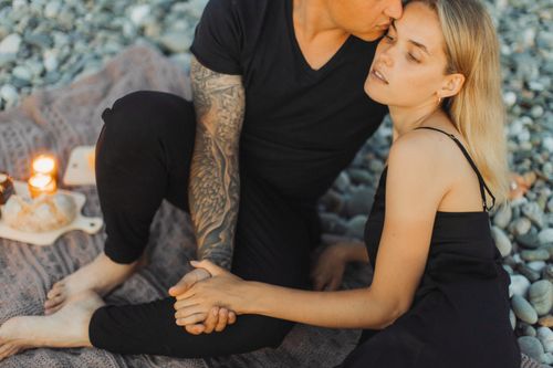 Free Couple sharing a romantic moment on the beach with candles and a cozy atmosphere. Stock Photo