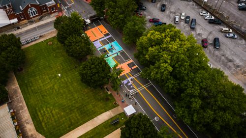 Free Drone view of narrow roadway with bright letters near grass meadow with trees and parking with transport Stock Photo