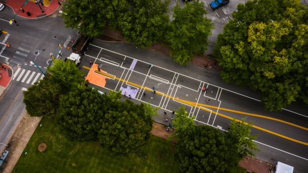 Drone view of road with colorful marking lines between meadow and trees in town