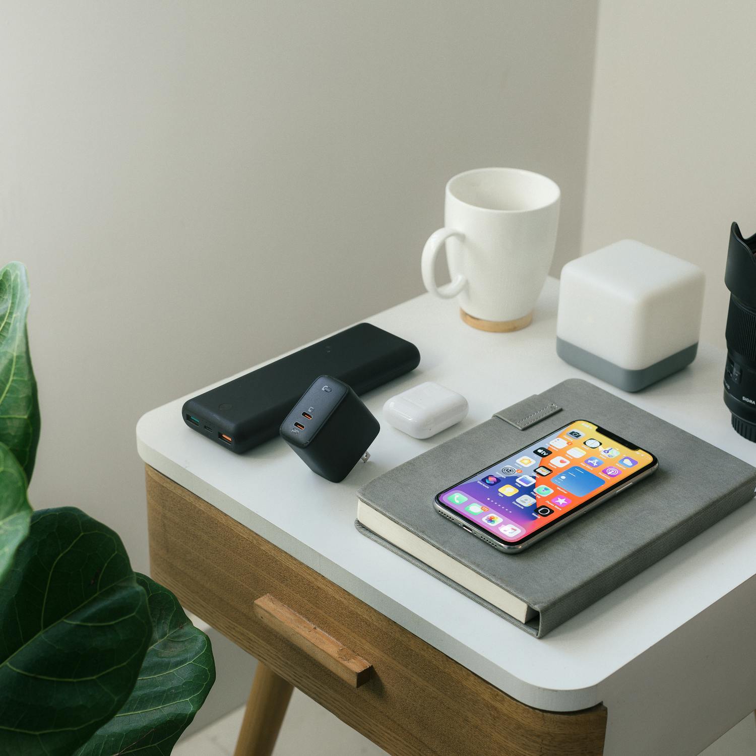 A neatly arranged desk featuring a smartphone, notebook, mug, and tech accessories, perfect for a modern workspace.