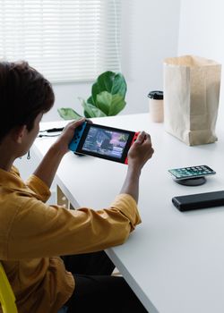 Teen playing Nintendo Switch at a minimalistic desk with natural light.