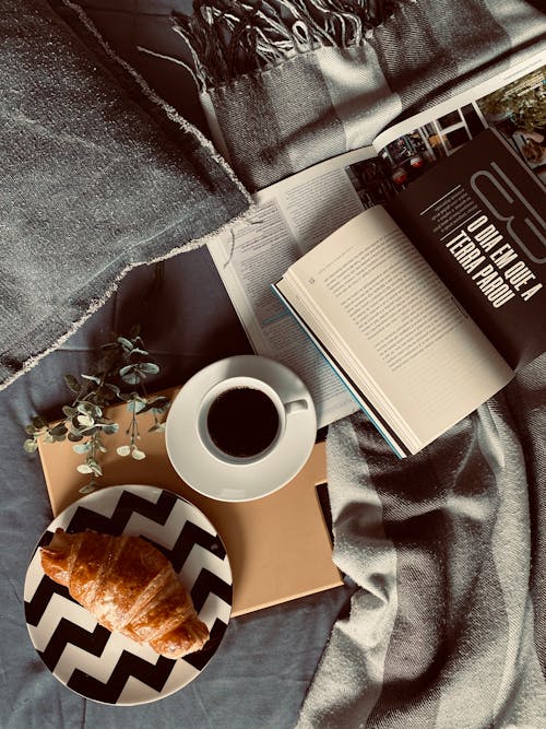 An Coffee and a Croissant beside an Open Book