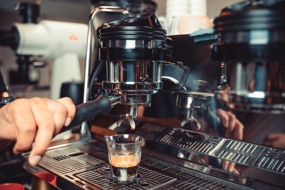 A close-up shot of a barista using an espresso machine to brew coffee.