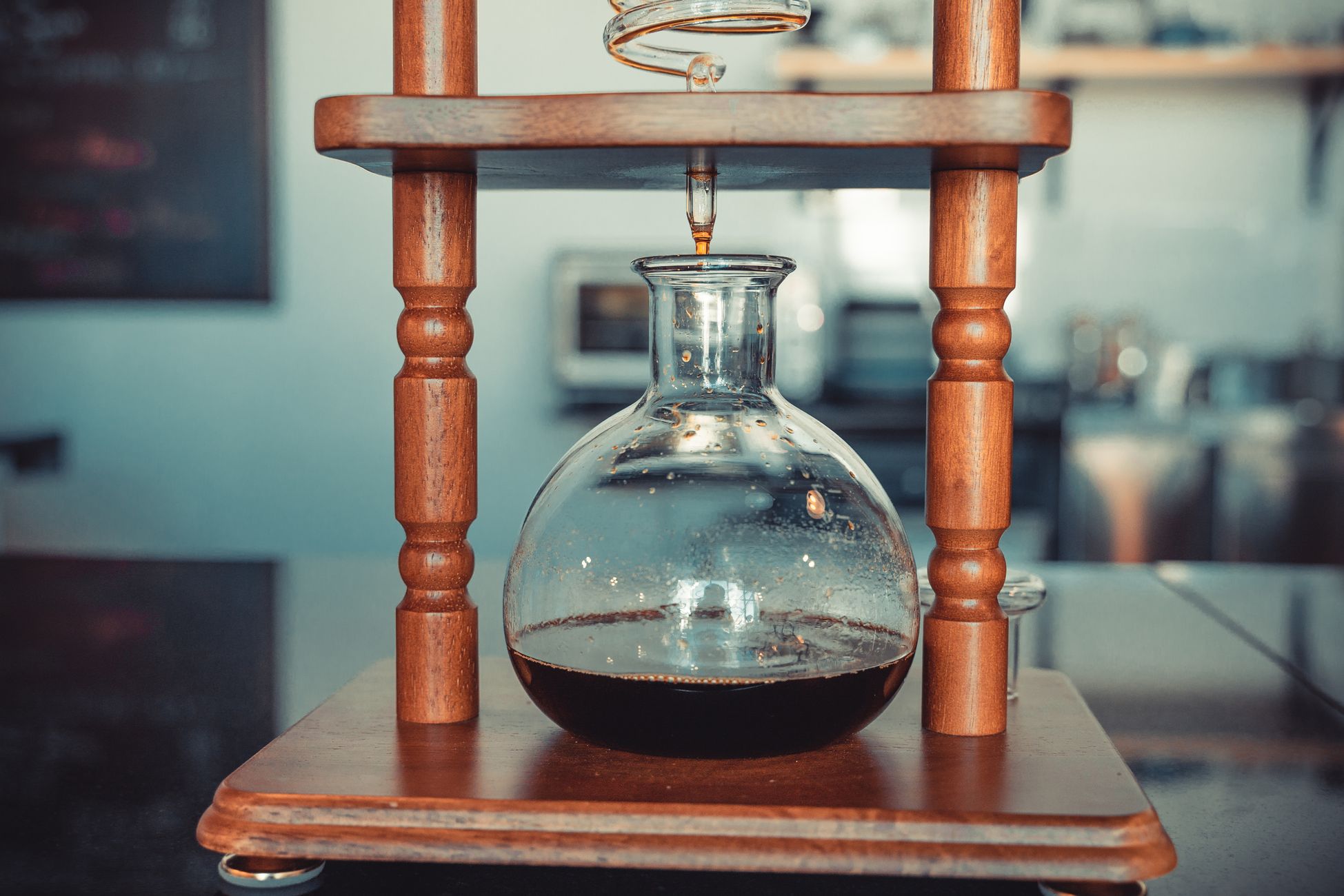 Detailed shot of a wooden drip coffee maker brewing fresh coffee in a cafe setting.