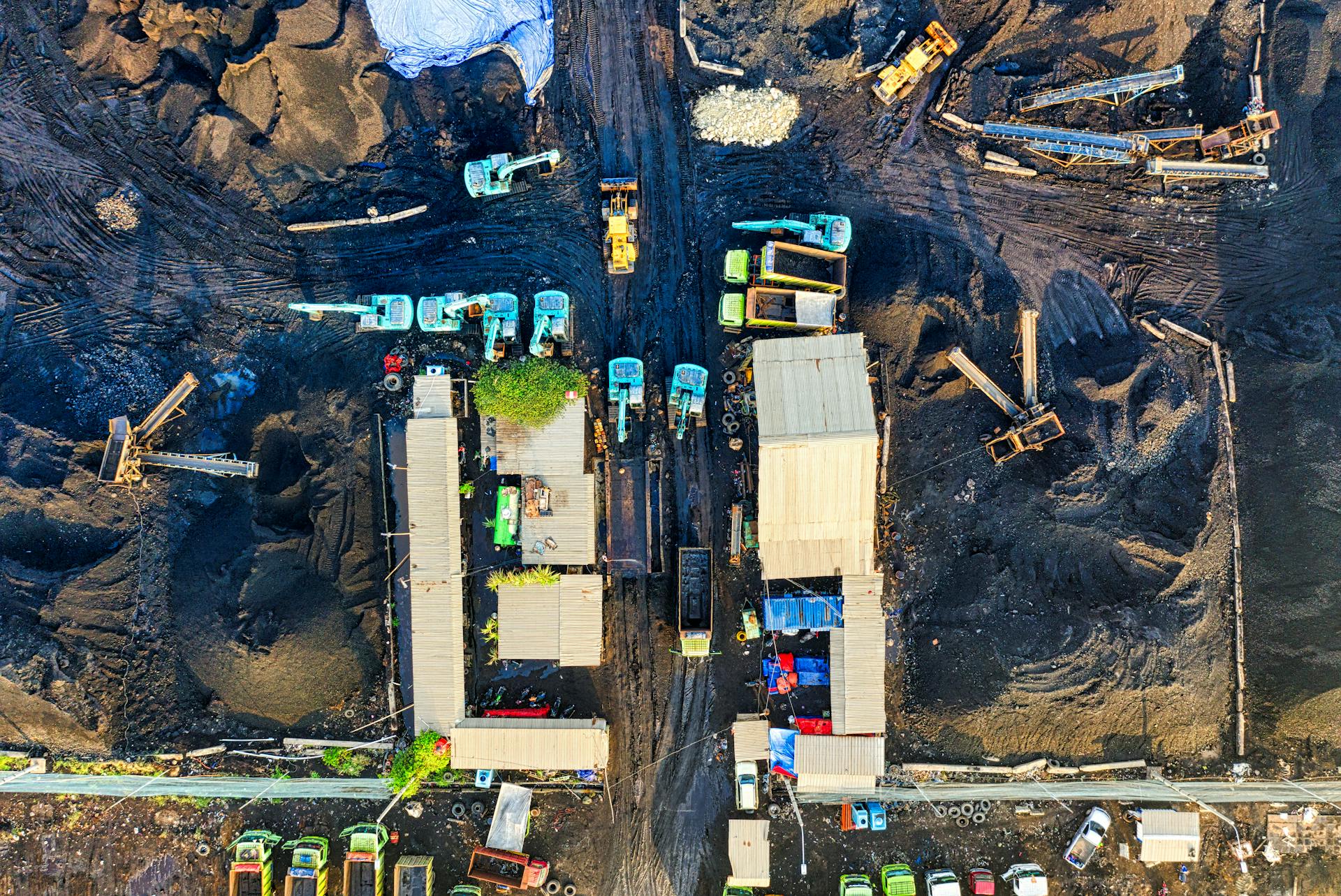 High-angle aerial view of a bustling construction site in North Jakarta, Indonesia with machinery and trucks.