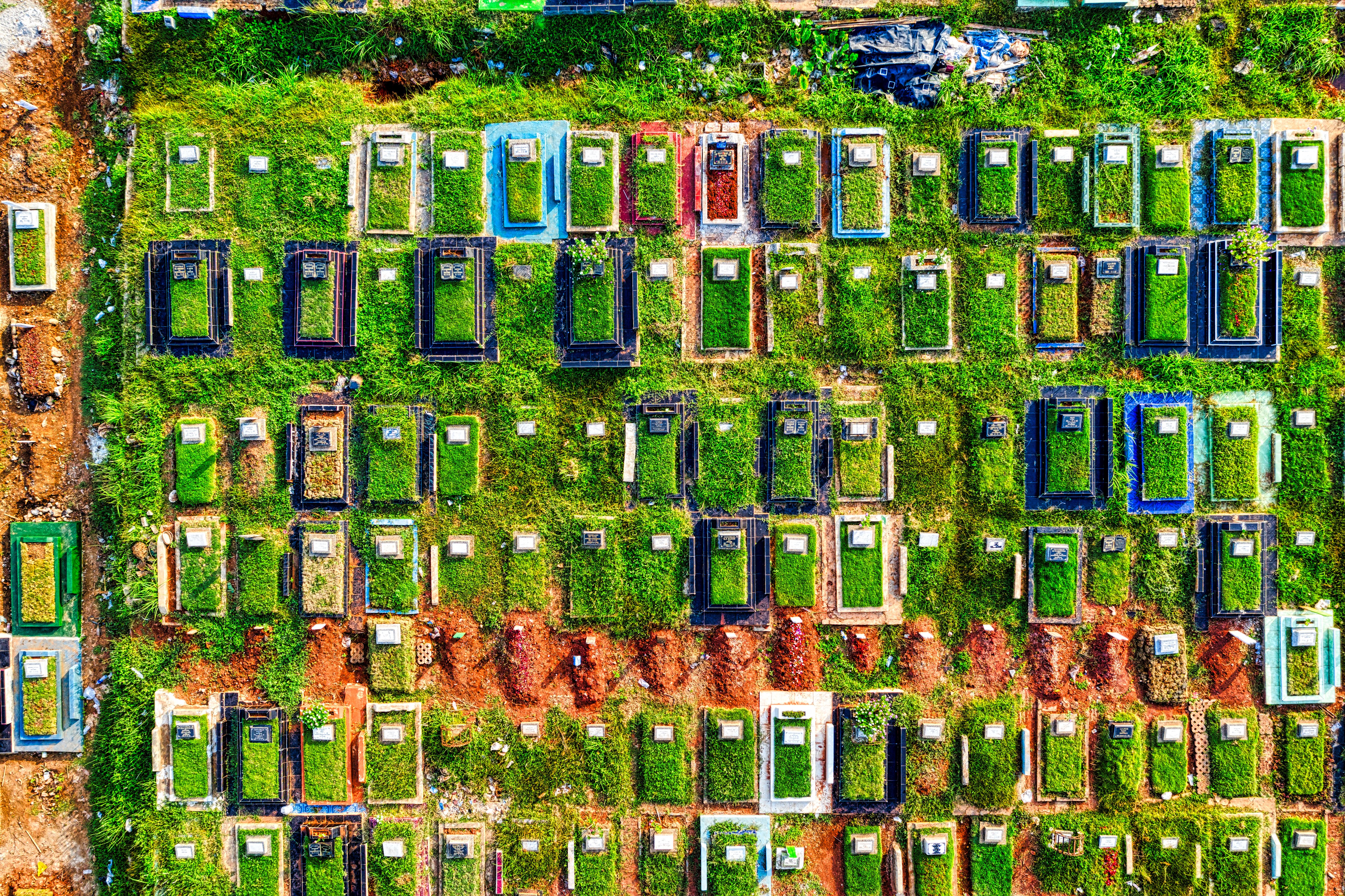 Aerial shot of a cemetery in Jakarta, showcasing colorful gravestones and lush greenery.