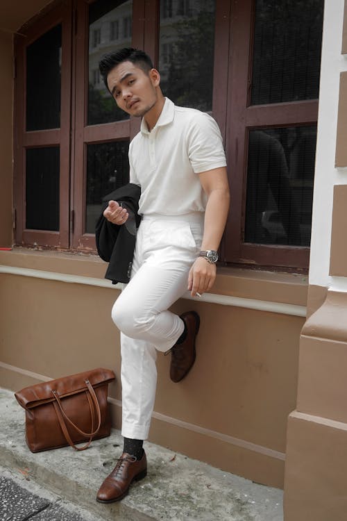 Free Man in White Polo Shirt and White Pants Smoking Outside Stock Photo