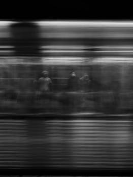 Black and white shot of unrecognizable person standing near window in subway car while riding