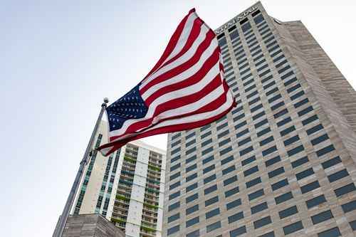 Free Low angle view of American flag and modern skyscraper in USA cityscape. Stock Photo
