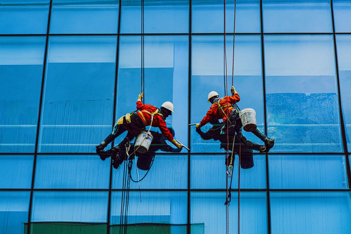 Operarios con cuerdas trabajando sobre el frente de un edificio