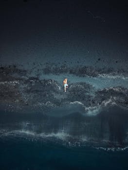 Drone shot of a man lying on black sand beach along the shore in Ramsar, Iran.