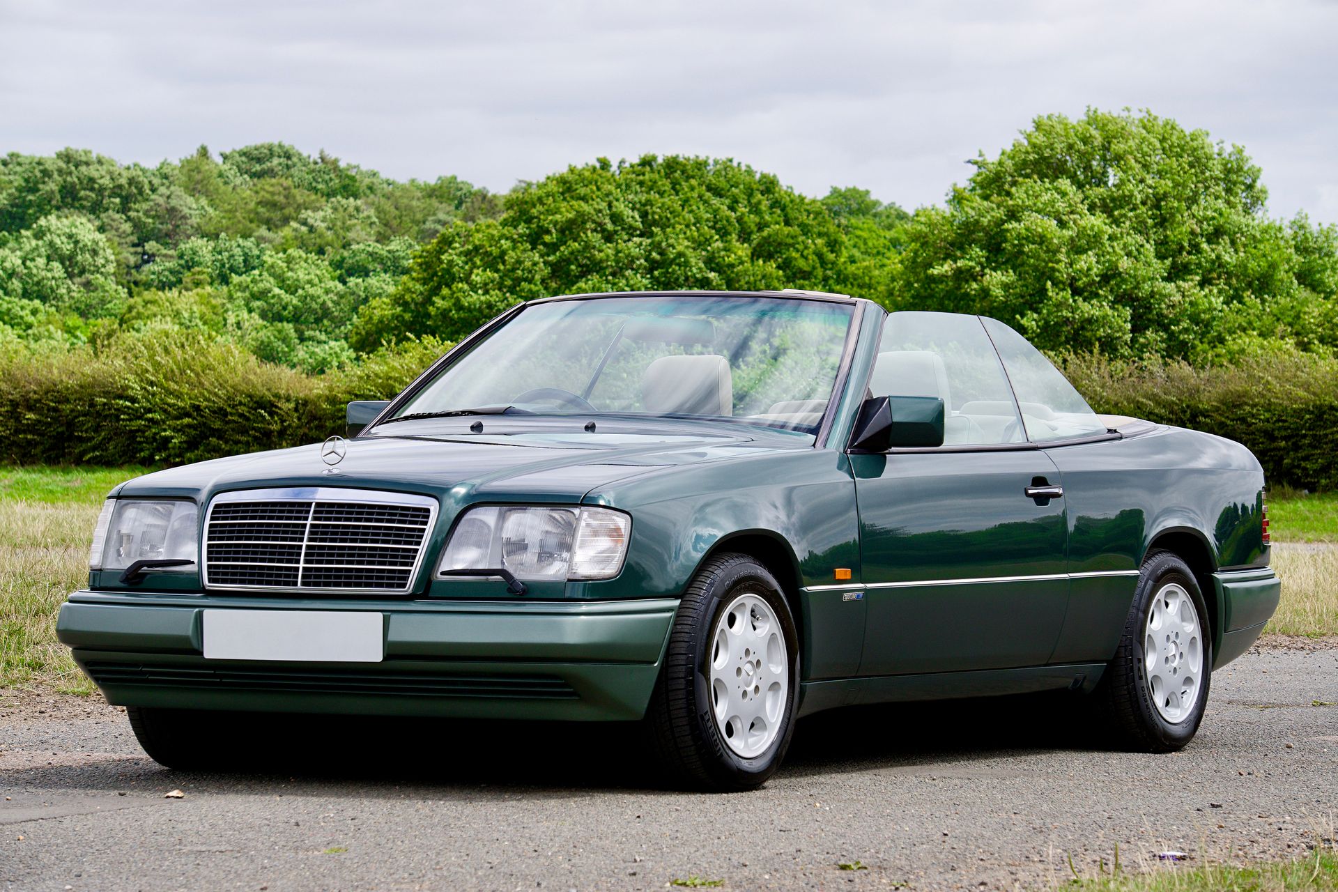 A vintage green convertible Mercedes-Benz in a beautiful outdoor UK landscape.