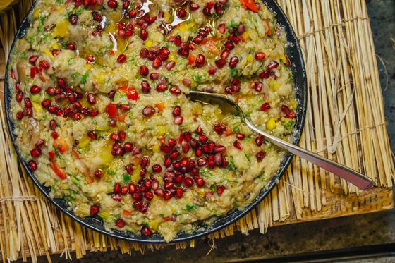 Round tray of chunky smoky eggplant mash with pomegranate seeds, peppers and olive oil