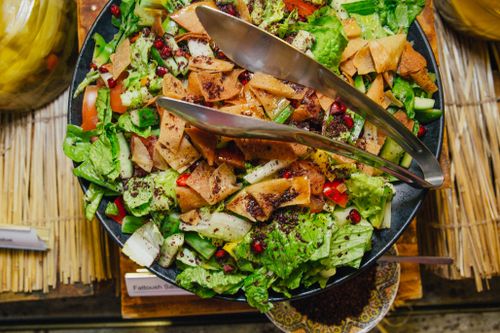 Free A vibrant Fattoush salad showcasing fresh vegetables, pita chips, and pomegranate seeds in a black bowl. Stock Photo