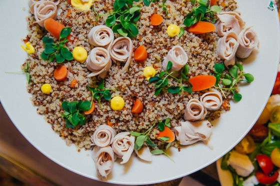 Red and white quinoa topped with rolled turkey slices, carrots, corn and pea shoots
