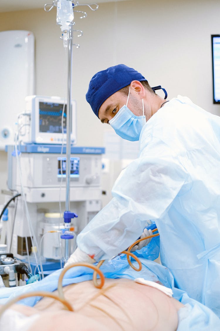 Doctor With Face Mask Taking Care Of Patient On Bed